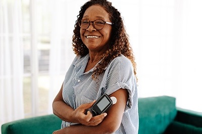 A woman smiles and holds her insulin pump