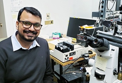 Dr. Abhishek Shrivastava seated next to a microscope.