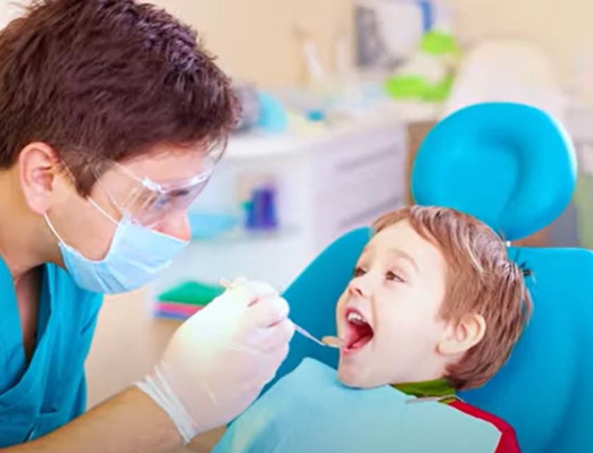 Un dentista revisa a un niño.