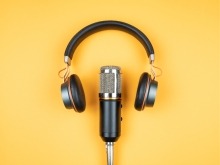 An image showcasing a podcast setup with a microphone and headphones against a bright yellow background.