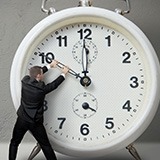 Person trying to turn back time on a clock