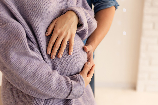 A pregnant woman gently holds her husband's hand, symbolizing their connection and support during this special time.