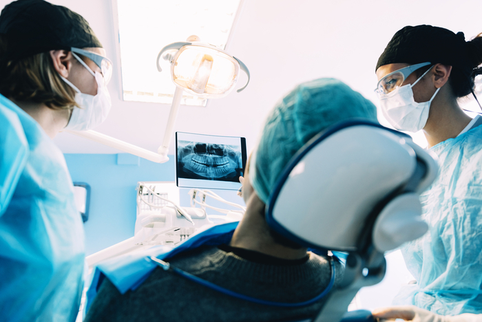 Two dental professionals with a patient in a dental chair