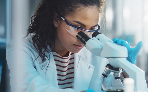 woman looking into microscope