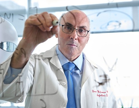 Drew Weissman writing a formula on a window.