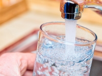 A person filling a glass with tap water.