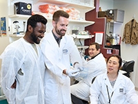 A group of researchers in the lab looking experiment results.