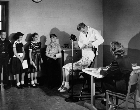 NIDR scientist Robert C. Likins examines school children in Grand Rapids, Michigan.