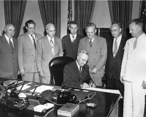 President Truman signs the National Dental Research Act. Standing, far right, is soon-to-be NIDR director Trendley Dean.