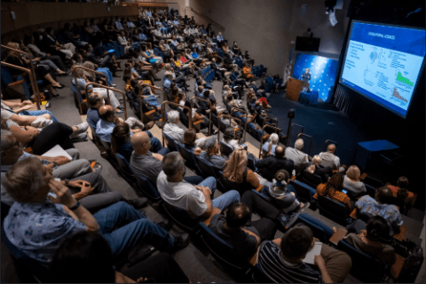 Many individuals gathered in a lecture hall, engaged in a presentation or discussion.
