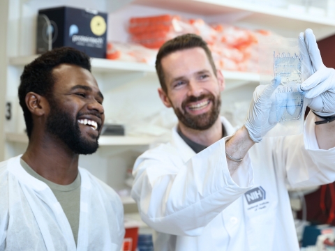 Two scientists in lab coats discussing an experiment