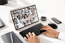 Person sitting at a laptop watching a virtual meeting.