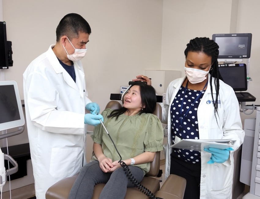 Two doctors talking to a patient who is sitting in a chair