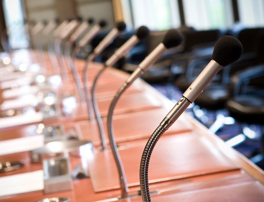 Empty panel table with microphones and chairs in the background