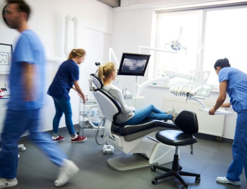 A female patient sitting in a dentist chair with three dentists working around her