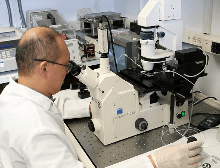A male researcher sitting and looking into a microscope