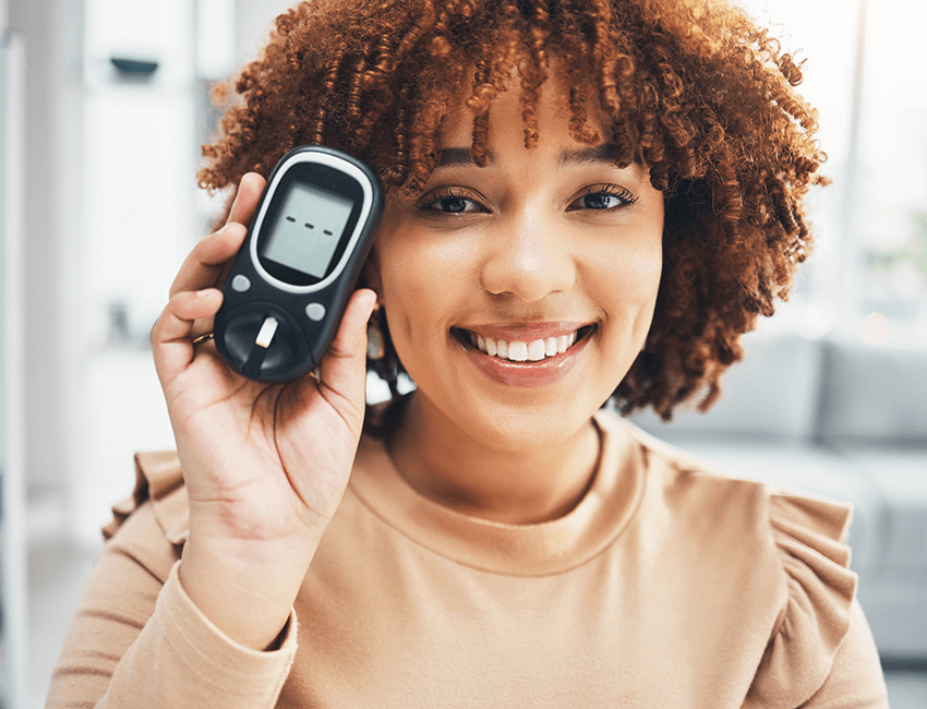 A smiling woman holds a glucose monitor