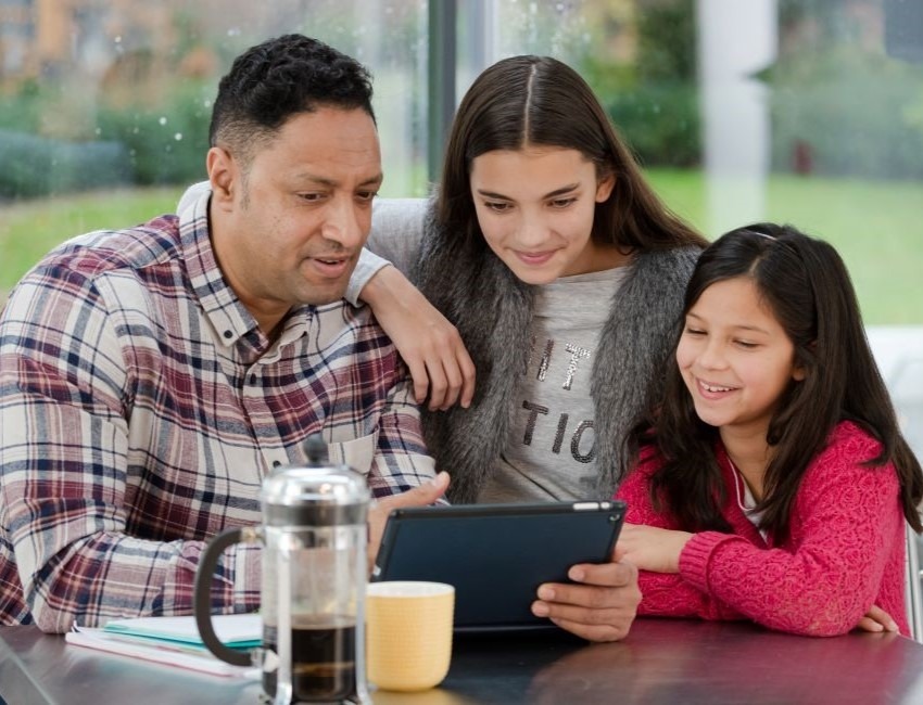 Una familia lee un artículo en una tableta electrónica.
