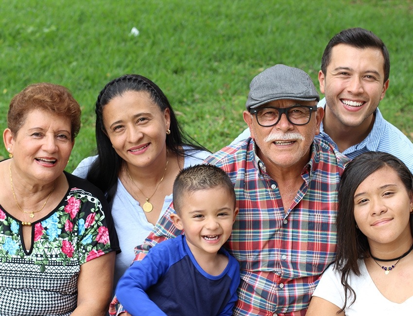 Varias generaciones de una familia hispana sentados juntos al aire libre.