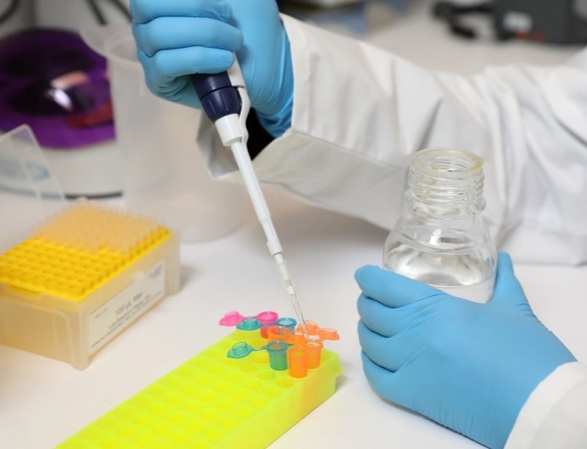 A scientist is working in a lab and using a pipette.