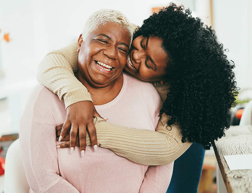 A family caregiver embraces an older woman
