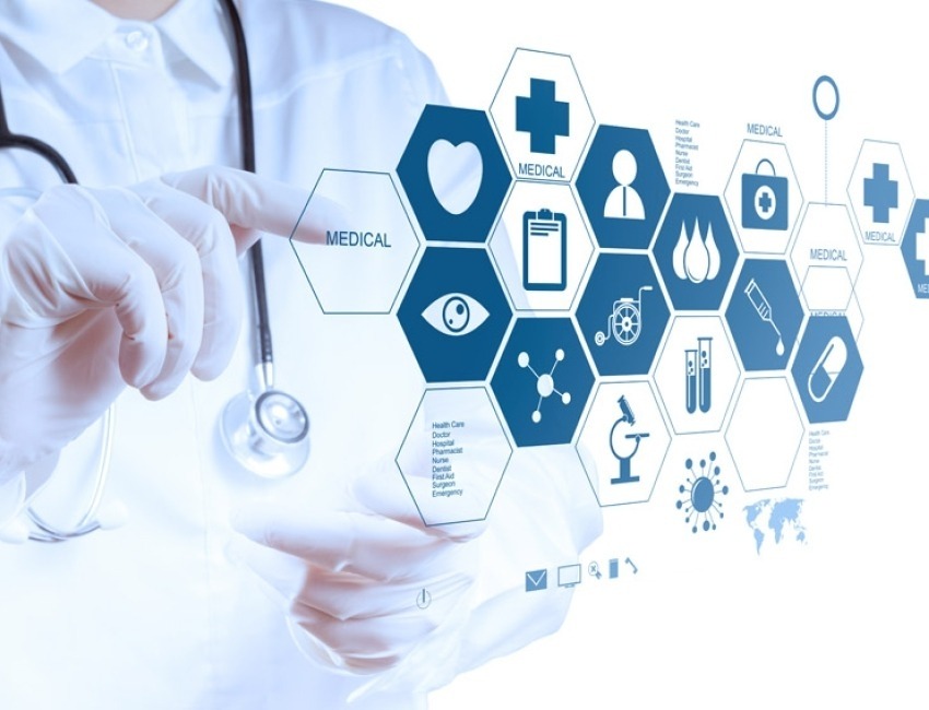 A scientist pointing to an illustration of many hexagons each with a different medical icon inside of it
