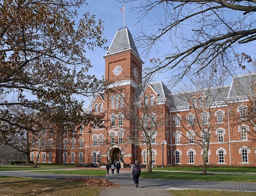 A brick college building in the fall with trees around it