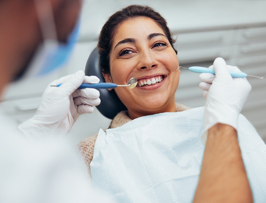 Woman smiling and getting her teeth cleaned