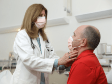 A photo of Dr. Rachel I. Gafni, a NIDCR Senior Research Physician, wearing a mask while examining a man's neck.