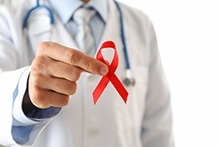 Doctor holding a red ribbon for HIV awareness
