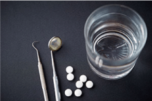 dental instruments, prescription pills and a glass of water